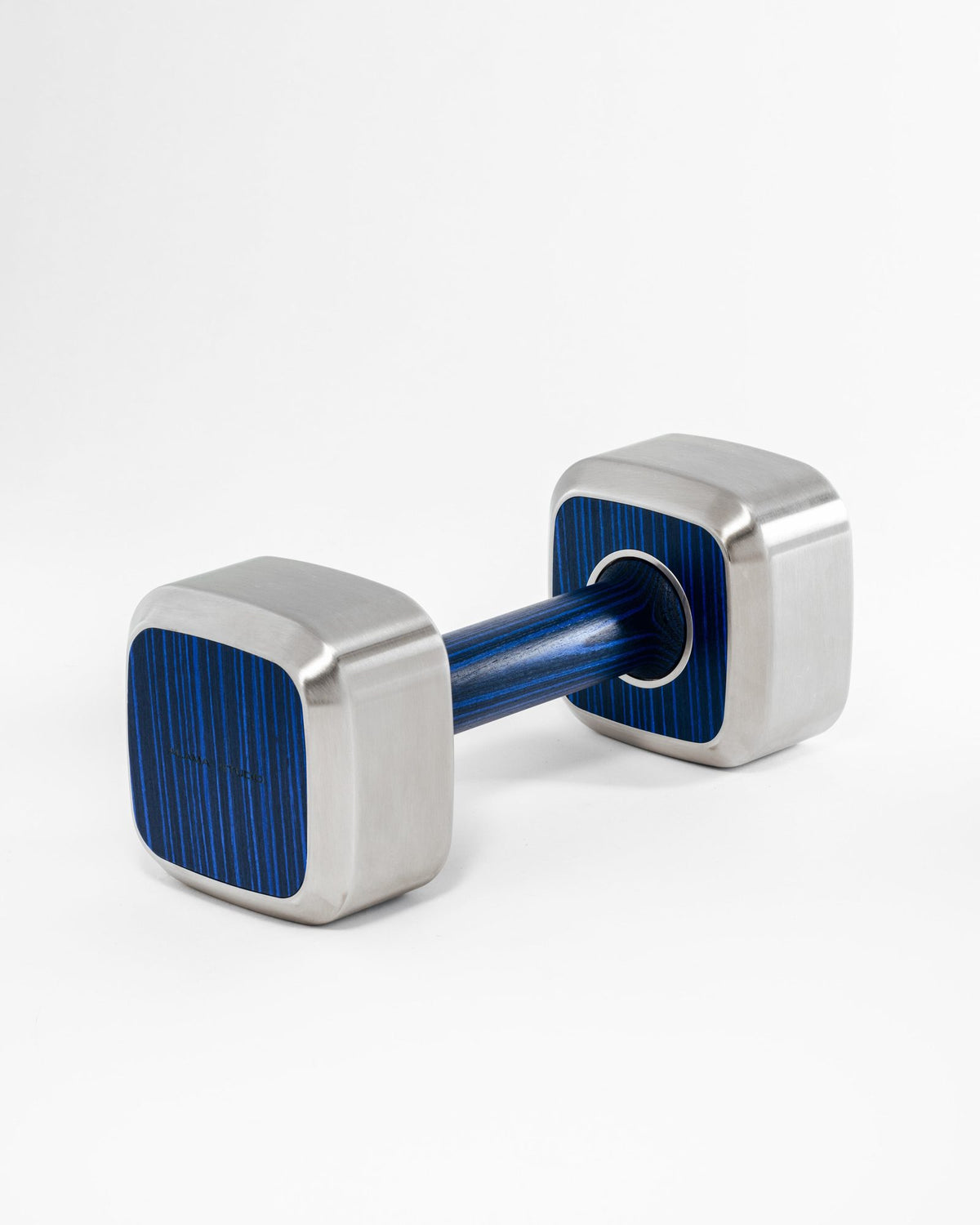 Alama Studio dumbbell with rounded square heads in brushed stainless steel, the faces and the handle in blue wood, on a pale grey ground.
