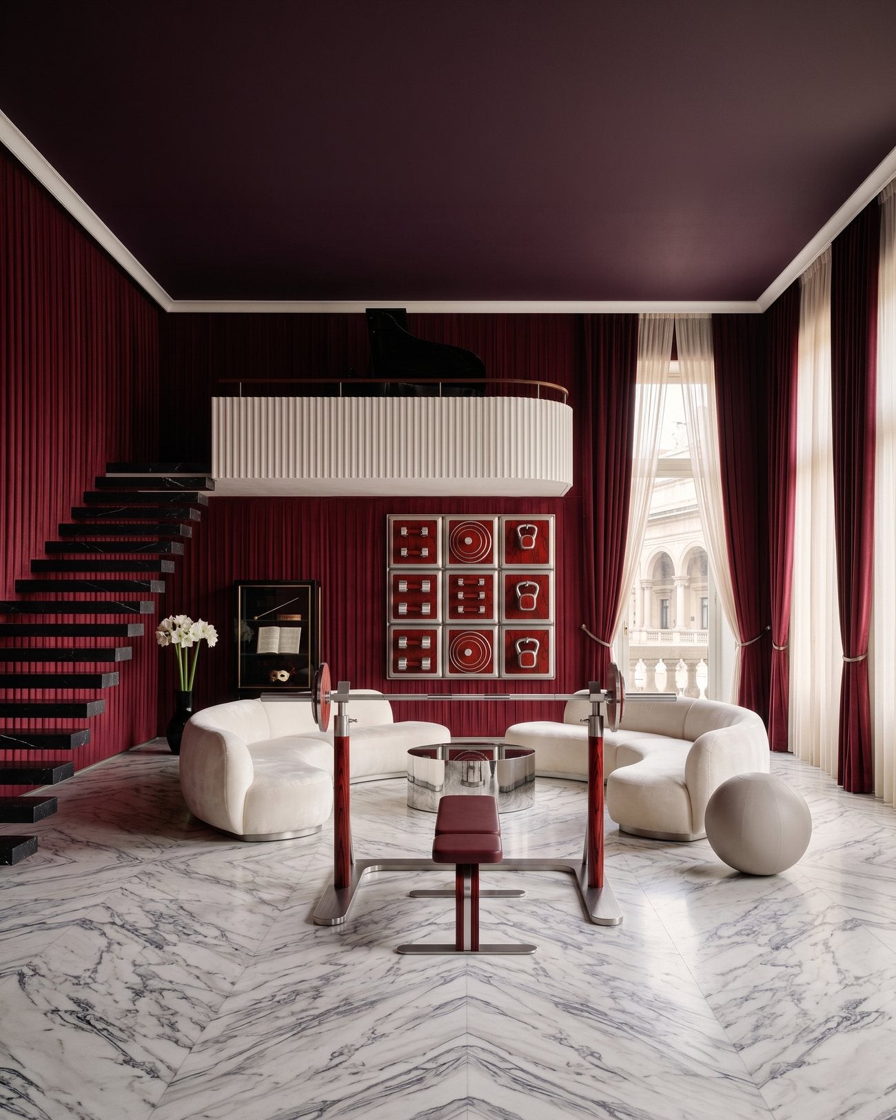 A Milanese palazzo living room in deep red, with an Alama wall display and barbell set against Arabescato marble.