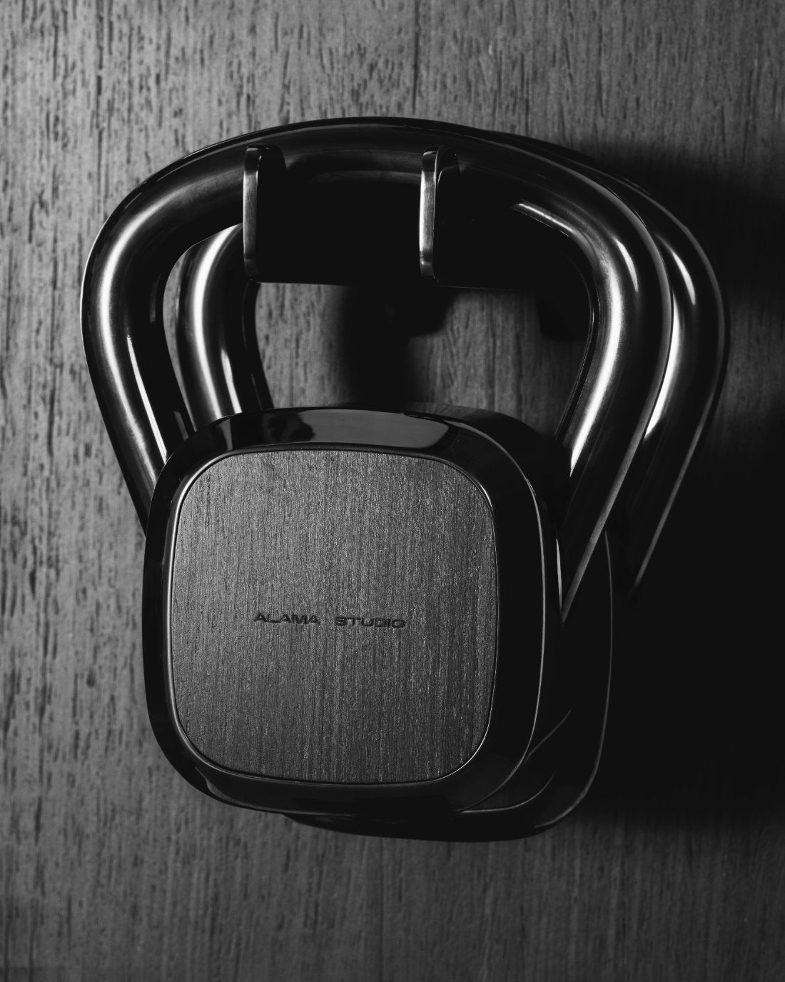 A whole Alama kettlebell in polished steel with an engraved wood face, a single sculpted profile.